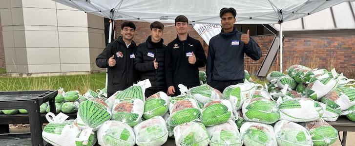Students giving thumbs up in front of a pile of frozen turkeys